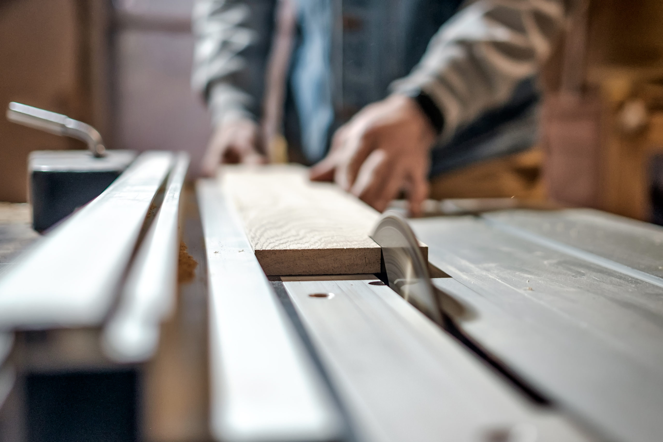 Worker cutting wood on table saw