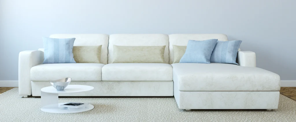 Cream-colored modern chaise sectional with blue and cream pillows.