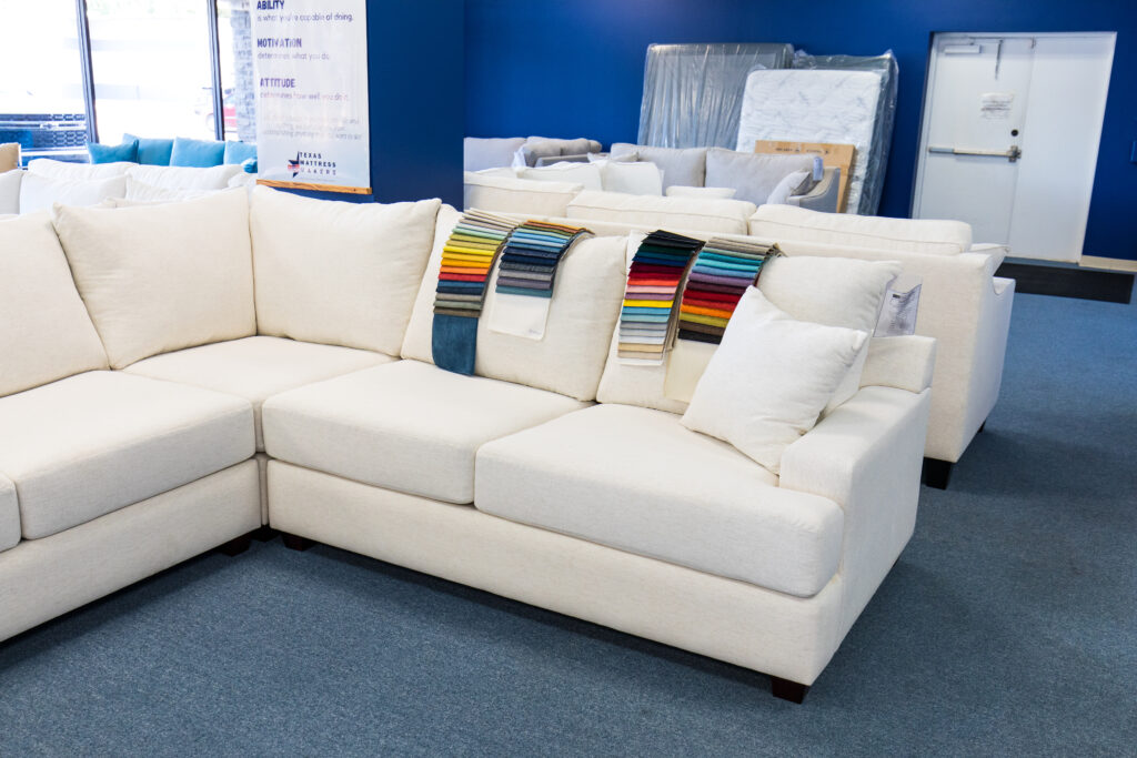White sectional with fabric swatches on top in the showroom.